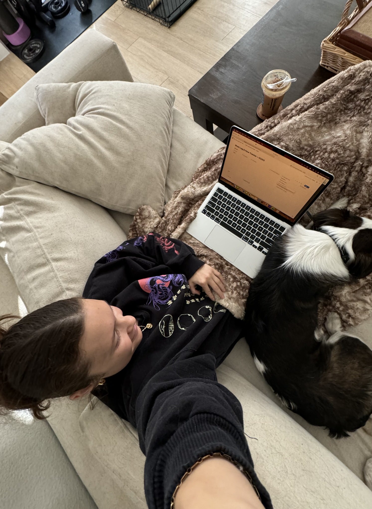 Business coach sitting on couch while getting done with her dog laying beside her